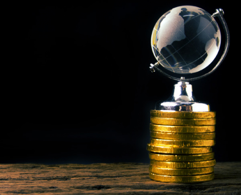 Globe atop stacked coins representing global financial planning and expat tax concerns for South Africans working abroad.