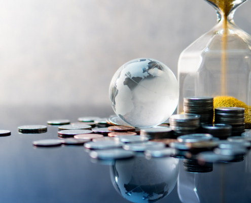 Glass globe on coins with hourglass representing global tax pressure and time-sensitive expat tax changes
