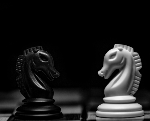 Close-up of black and white chess knights representing the complex choices in Double Tax Agreement relief.