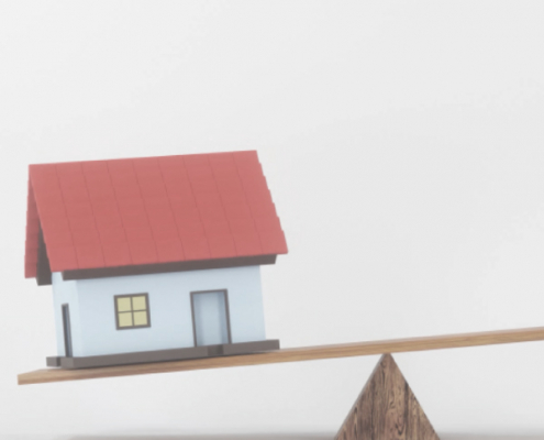 Model of house on a balance scale, representing tax residency considerations for expats.