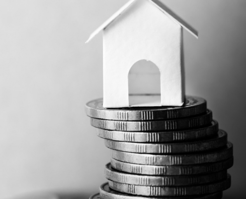 Model house placed on a stack of coins symbolizing property investment and tax in South Africa