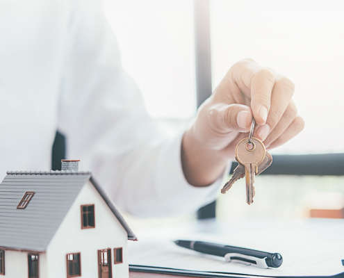 Keys in hand with a house model representing ceasing tax residency and expat tax process.