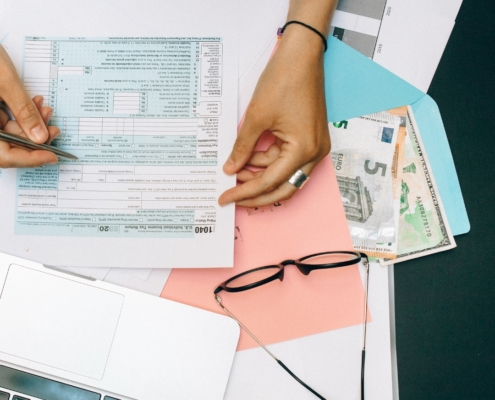 Tax form and currency with glasses and laptop showing non-resident taxpayer filing process.